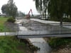 Eine Holzbrücke über den Bach wird repariert und um 30 Zentimeter höher gelegt