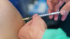 Ein medizinischer Mitarbeiter impft eine Frau. Foto: Jörg Carstensen/dpa/Symbolbild