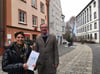 Vorsitzender Rolf Merz und Beirätin Ursula Klozbücher (von rechts) stehen vor der Geschäftsstelle des Vereins Haus und Grund Ellwangen in der Schmiedstraße 6. Sie weisen mit einer Festschrift auf das 100-jährige Bestehen des hin.