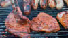 Bratwürste und Steaks auf einem Holzkohlegrill. Trotz höherer Nachfrage während der Fußball-Weltmeisterschaft sollen die Preise für Grillfleisch nicht steigen.