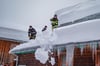 Feuerwehrleute räumen Schneemassen von einem Dach in Eisenerz. 