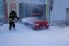 
 Ein Feuerwehrmann löscht ein Auto.
