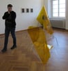 Ein Besucher begutachtet eine Installation von Friedrich-Daniel Schlemme, die im Raum schwebt und an ein Fluggerät erinnert.