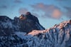 Bayern, Pfronten: Der Gipfel des Aggensteins und der Schnee auf den Skipisten des Breitenbergs leuchten im Licht der aufgehenden Sonne rötlich.