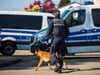 Ein Polizist läuft mit einem Polizeihund an einem Polizeiauto vorbei. Foto: C. Schmidt/Archiv