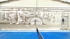  An der Wand entsteht ein dynamisches, in Grautönen gehaltenes, großes Abbild mehrerer Tennisspieler inmitten eines Matches.