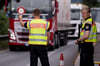 Polizisten kontrollieren Fahrzeuge, die aus Österreich nach Deutschland kommen. Transportunternehmen befürchten massive Einbußen durch strengere Grenzkontrollen und lange Staus.