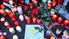 Kerzen und Blumen stehen an einem Tatort.