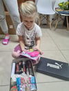 Dieses Mädchen packt einen Schuhkarton voller Geschenke aus.