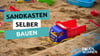 Eine Nahaufnahme eines Sandkastens mit einem Spielzeuglaster im Sand