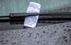 Ein Knöllchen steckt bei Regen unter dem Scheibenwischer eines Autos, das falsch geparkt wurde.