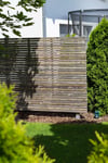 Ein simpler und minimalistischer Sichtschutz aus Holz erschafft in Einklang mit der modernen Architektur des Hauses ein stimmiges Bild und einen Rückzugsort. 