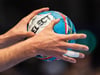 Ein Handballer hält den Spielball in den Händen.